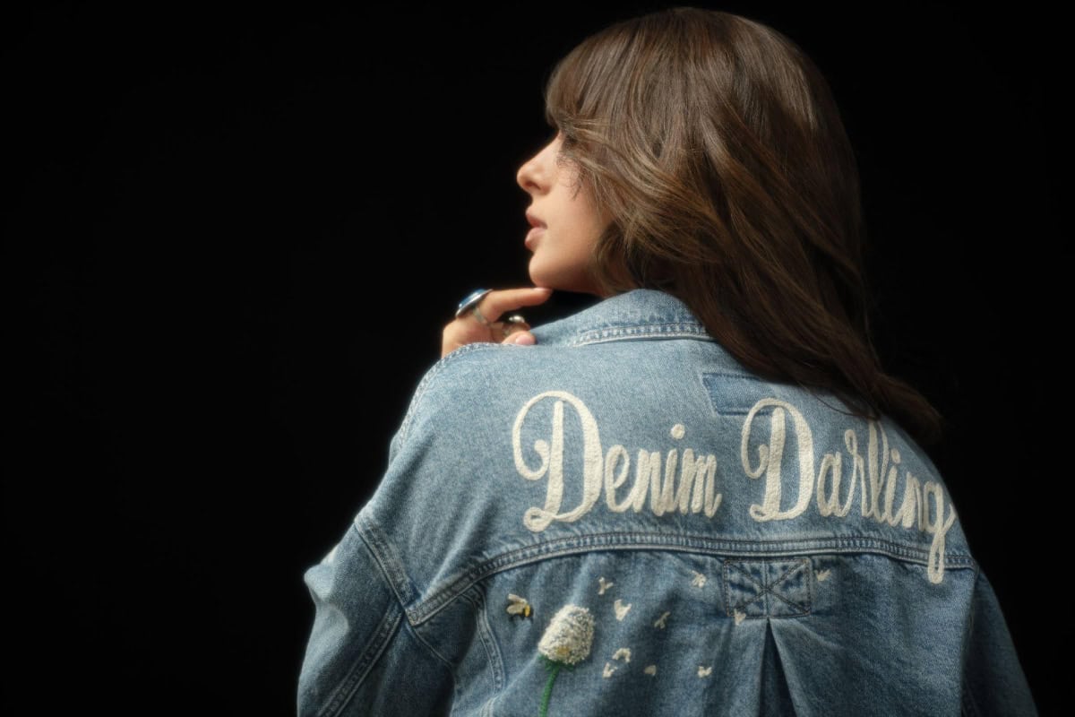 Ella Langley wearing a denim jacket with "Denim Darling" text on back, promoting American Eagle.